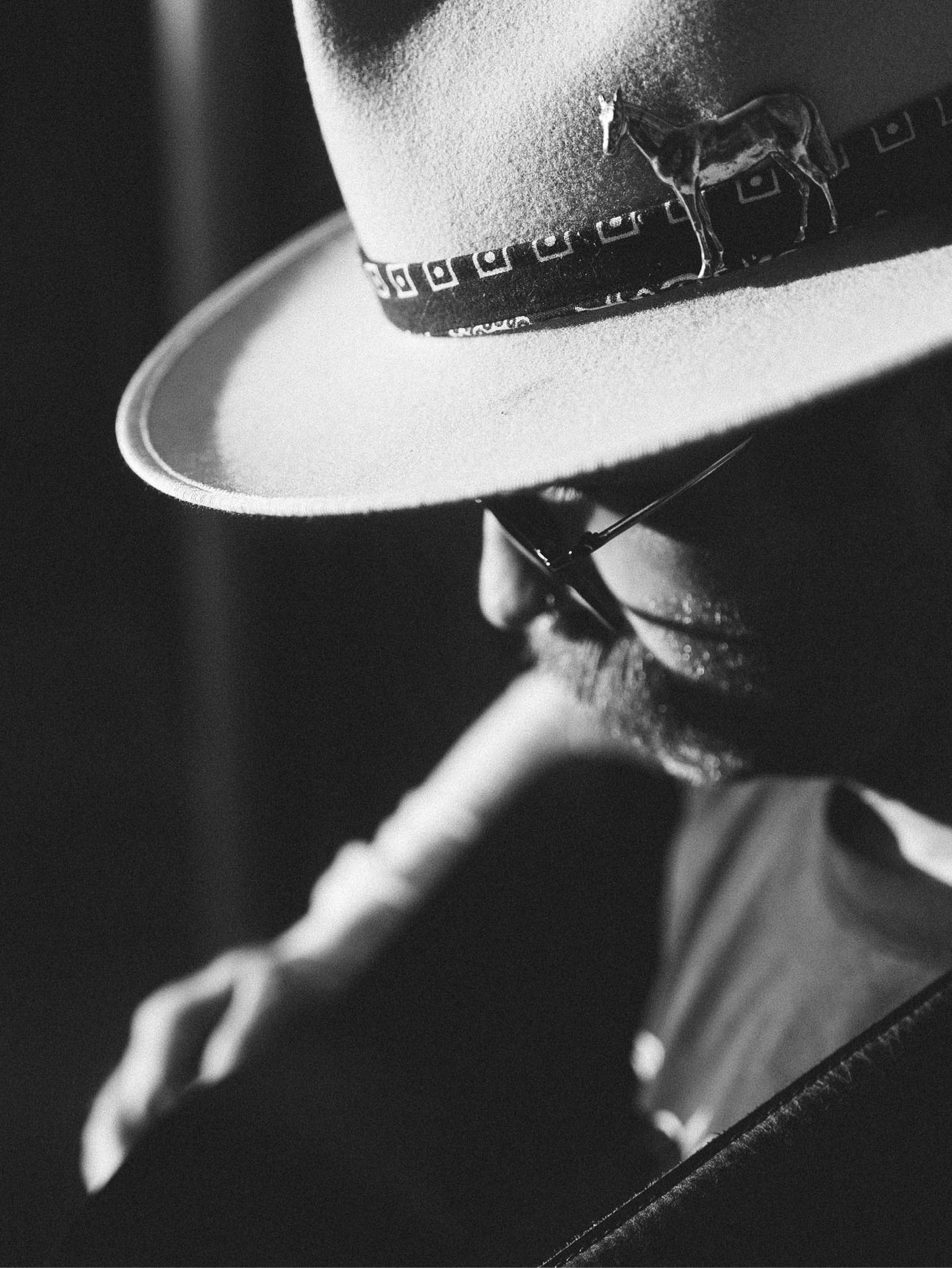 Black and white close-up of a hat with a horse pin on the band