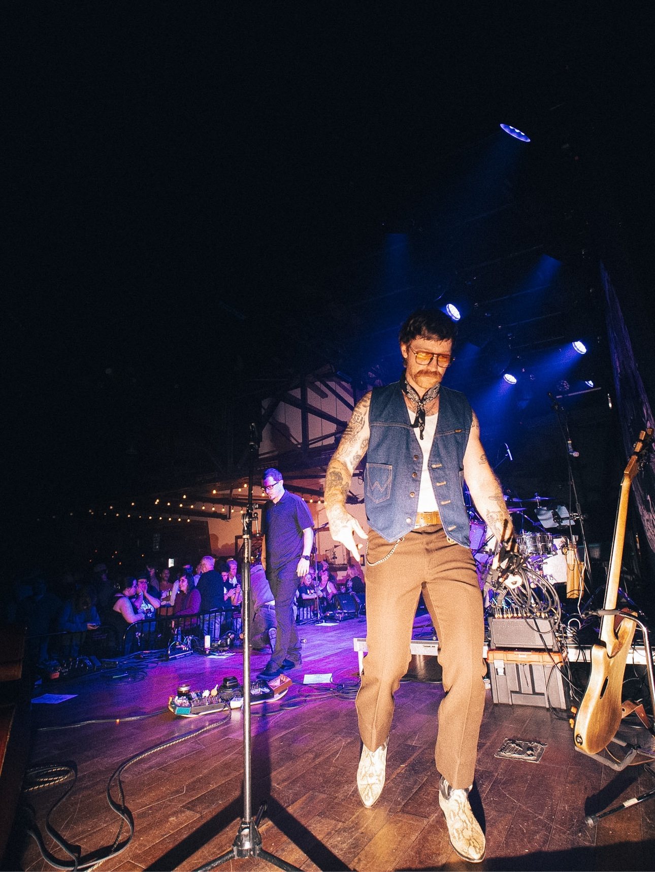 Trappers Pass walking the stage in a denim vest and snakeskin boots